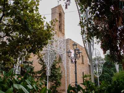 Avvicinandoci alla facciata in pietra, coperta da alberi e luminarie temporanee...